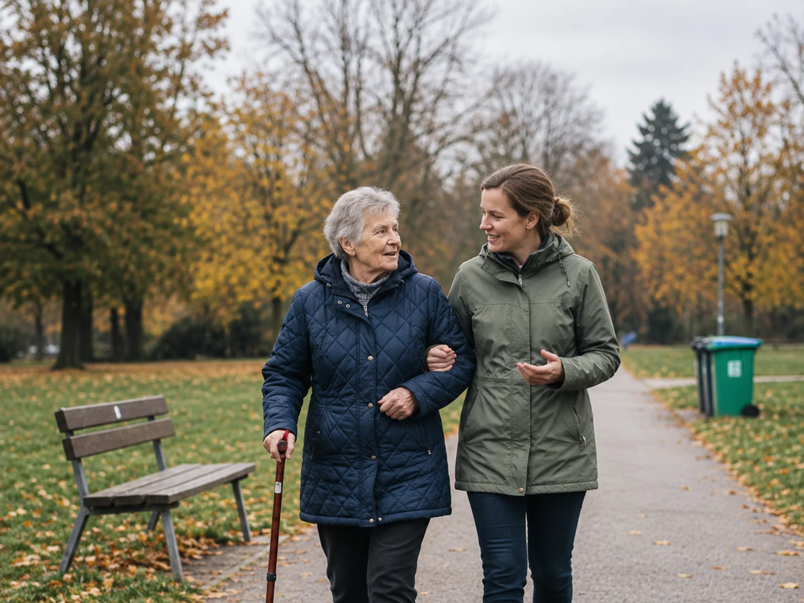 Alltagsbegleiterin begleitet eine Seniorin bei einem Spaziergang im Park