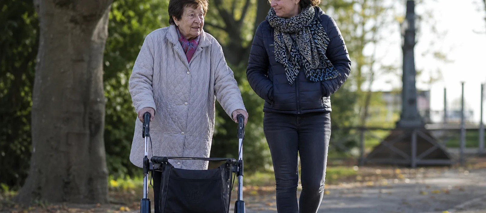 Natur und Gesundheit im Alter: Studien und praktische Tipps | Sonnenseite Alltagshilfen Senior mit Rollator spaziert mit Begleiterin durch einen Park – Bewegung und Natur stärken die Gesundheit im Alter.